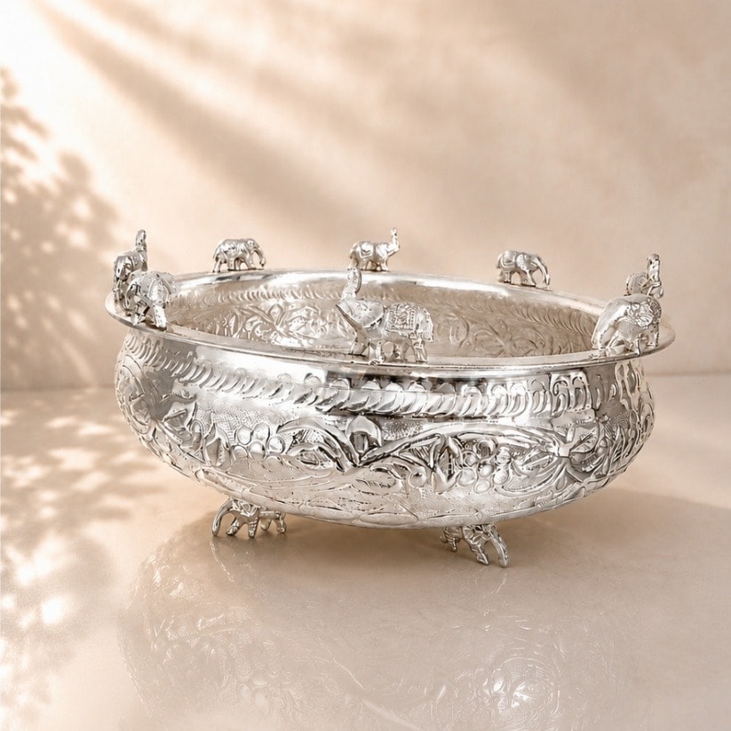 A silver-plated urli bowl with elephant motifs along the rim and hand-embossed detailing